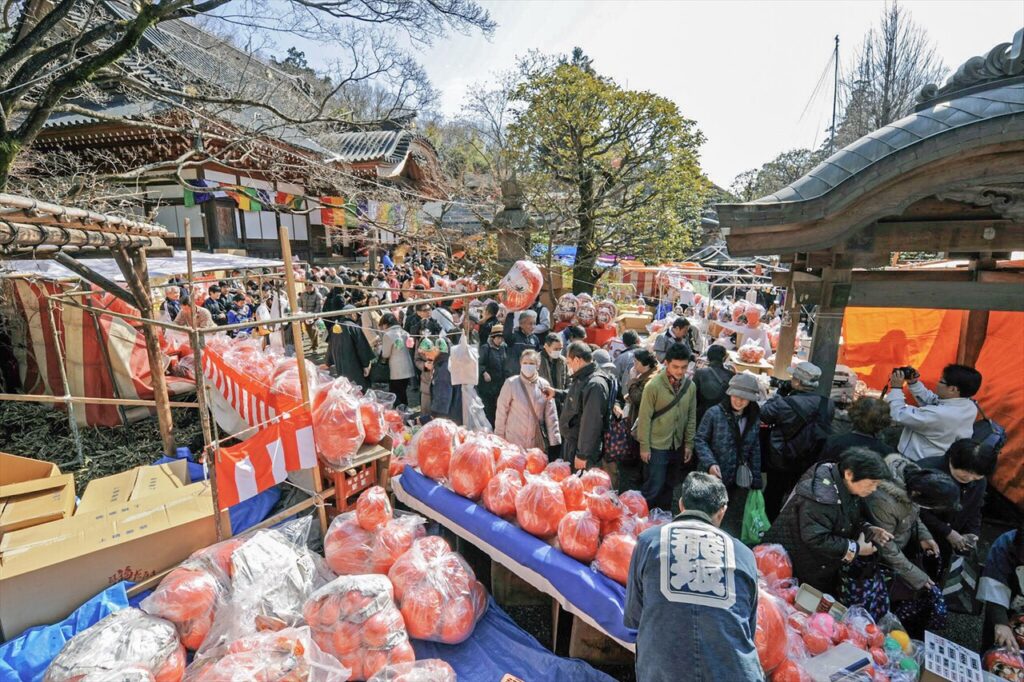 深大寺の境内で開催される有名な「日本三大だるま市」。参拝客と無数のダルマが並ぶ活気ある風景