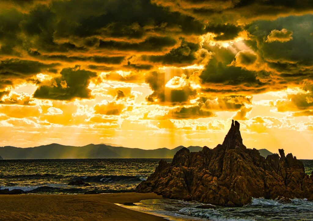 水晶浜の夕日の写真。雲の間から光が差し込むドラマチックな空と海の風景が広がる、福井県美浜町の美しいビーチの夕景。