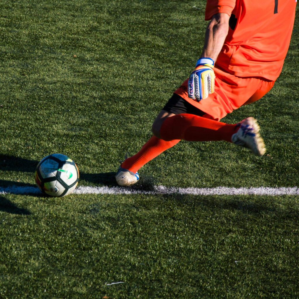 A player wearing a red jersey and socks is about to kick a soccer ball.