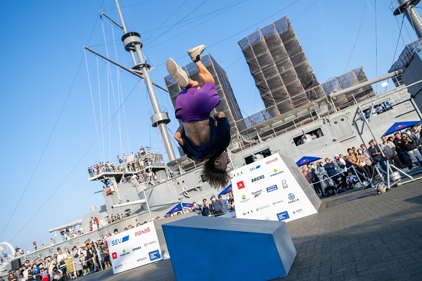 Parkour athlete performing a mid-air flip during a past Parkour Top of Japan event in front of the Battleship Mikasa in Yokosuka.