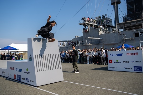 Parkour athlete scaling an obstacle during a past Parkour Top of Japan event at Mikasa Park in front of the Battleship Mikasa in Yokosuka.